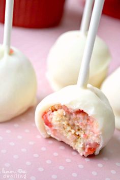 cake pops with white frosting and strawberries in them on a pink tablecloth