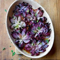 a bowl filled with red onions on top of a wooden table