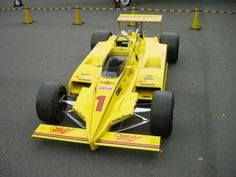 a yellow race car sitting on top of a parking lot