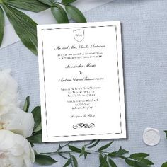 a wedding card with white flowers and greenery on the side, next to a wax seal