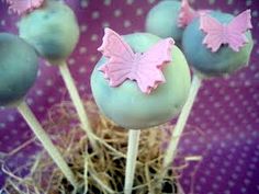 some cake pops with pink icing on top of straw and grass in front of a polka dot background