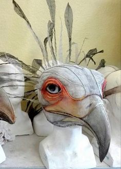 there are two masks with feathers on top of each head and one has an orange eye