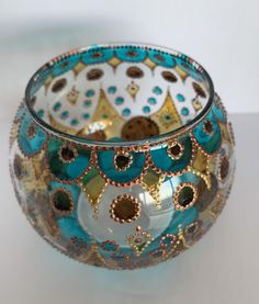 a glass bowl with gold and blue designs on the rim, sitting on a white surface