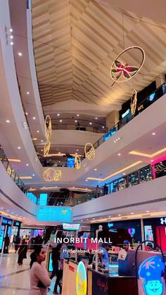 the interior of a shopping mall with people walking around and lights hanging from the ceiling