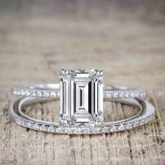 an emerald cut engagement ring on top of a wooden table