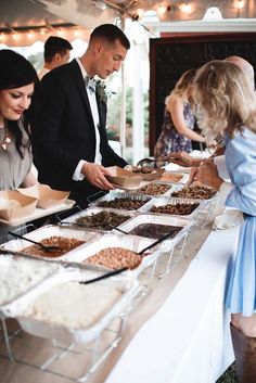 people standing around a buffet table with food on it