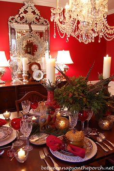 a table topped with lots of gold and red vases filled with flowers next to candles