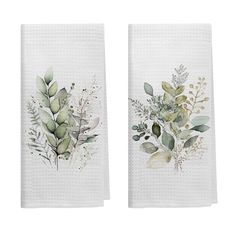 two white towels with green leaves and plants printed on the front, one is folded in half