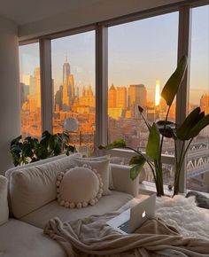 a living room filled with furniture and large windows overlooking the cityscape at sunset