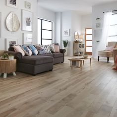 a living room filled with furniture and lots of wood flooring next to large windows