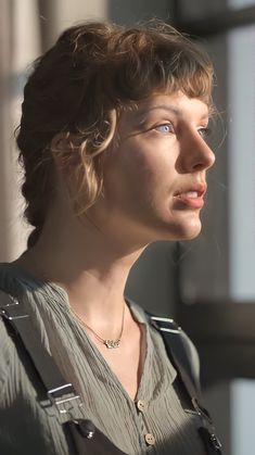 a woman with curly hair is looking off into the distance while standing in front of a window