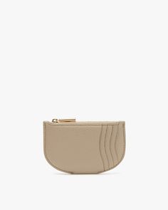 Small purse with a curved bottom and zipper on top. Modern Beige Wallets For Daily Use, Chic Compact Wallet For Everyday Use, Chic Compact Everyday Wallet, Modern Wallets For Everyday Use, Minimalist Everyday Wallet With Zipper Closure, Classic Beige Wallet For Everyday Use, Modern Beige Wallets For Everyday Use, Classic Beige Wallets For Everyday Use, Modern Beige Wallet For Everyday Use