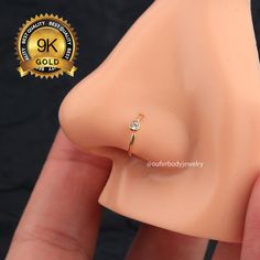 a fake nose ring with a single diamond on it's side, in front of a black background