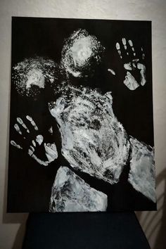 a hand and foot prints on a black background, with white ink in the foreground