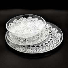 three glass plates stacked on top of each other with lacy doily design in the middle