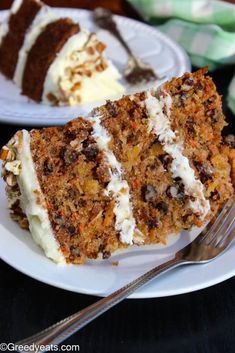 a slice of carrot cake with white frosting on a plate next to a fork