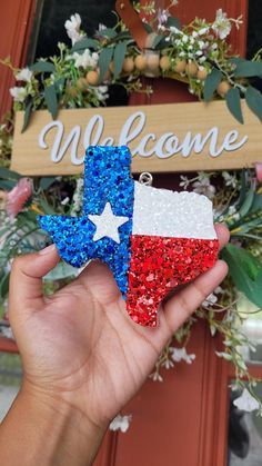 someone holding up a patriotic star shaped ornament in front of a welcome sign