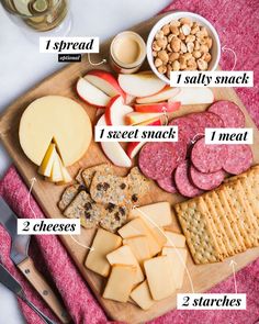 a wooden cutting board topped with cheese, crackers and meats