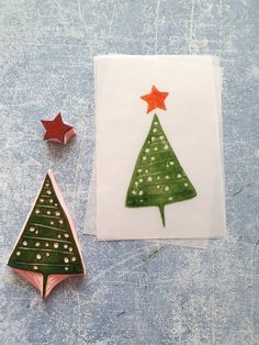 two christmas trees are next to each other on a blue surface with red and green stars