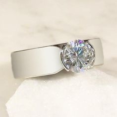 a diamond ring sitting on top of a white marble surface with the center stone in the middle