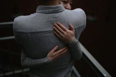 a woman is hugging her husband on the stairs