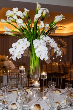 a vase filled with white flowers sitting on top of a table covered in silverware