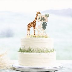 a giraffe cake topper sitting on top of a white cake