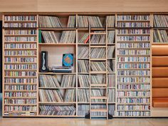 a large book shelf filled with lots of books and cds on top of wooden shelves