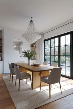 a dining room table and chairs in front of large windows