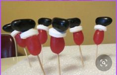 five red and black toothpicks with santa's hats on them sitting on top of a table