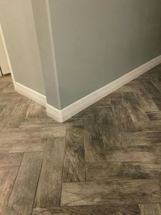 the corner of a room that has wood flooring on it and a gray wall