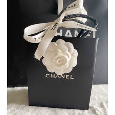 a chanel bag with a flower on the front and white ribbon around the handle