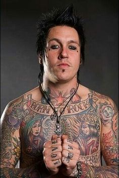 a man with lots of tattoos on his chest and hands holding something in front of him