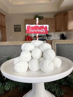 a white cake plate topped with snowballs and a sign