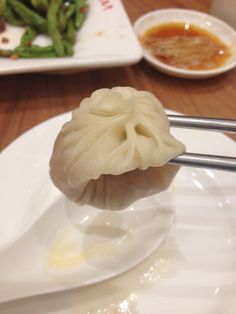 a dumpling on a spoon with broccoli and sauces in the background