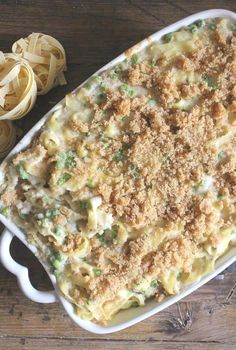 a casserole dish filled with pasta and meat crumbs on a wooden table