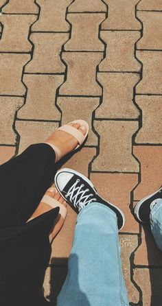 two people standing next to each other on top of a brick walkway with their feet in the air