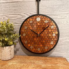 a clock made out of coins sitting on top of a wooden table next to a potted plant