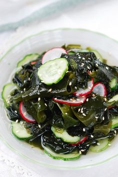 a white plate topped with greens and cucumbers