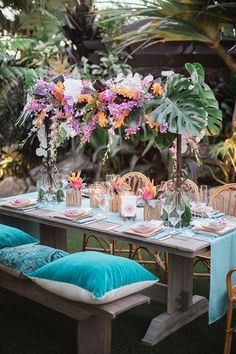 the table is set with colorful flowers and place settings for guests to sit down at