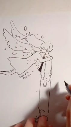 someone is drawing an angel on paper with a marker and pencils in their hands