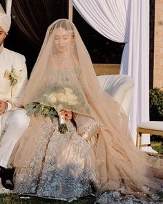 a man and woman dressed in wedding attire sitting next to each other on a chair