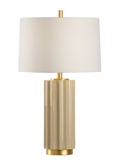 a table lamp with a white shade on it and a gold metal frame around the base