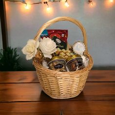 a wicker basket filled with chocolates, cookies and tea sits on a wooden table