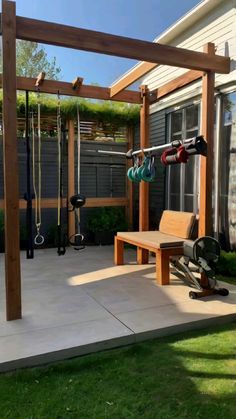 a wooden bench sitting under a pergolated trellis next to a wall mounted gym