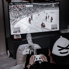 a person sitting in front of a tv holding a nintendo wii game controller while playing hockey