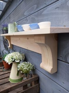 a wooden shelf with vases and flowers on it next to a wall mounted potted planter