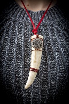 a woman wearing a necklace with a wooden pendant on it's neck and a red cord