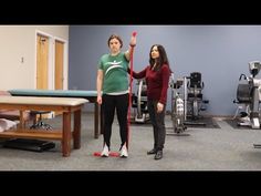 two women standing in a room with exercise equipment on the wall and one holding a pole