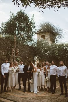 a group of people standing next to each other in front of some trees and bushes